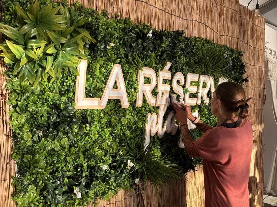 Pose d'une enseigne en lettres découpées « La Réserve Plage » sur un mur végétal, par l'équipe de L'Arène de la Com